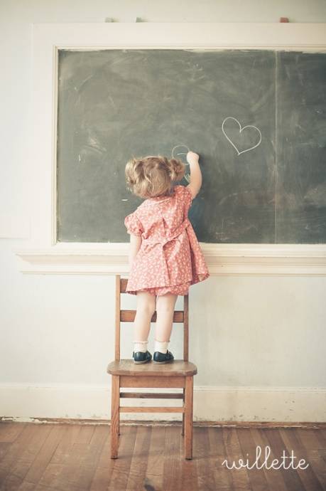 Девочка рисует на школьной доске сердечки