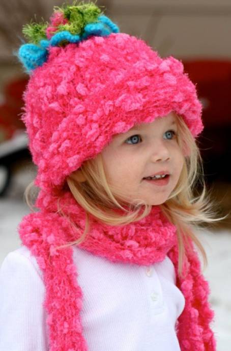 Белокурая девочка в розовой шапке и шарфе