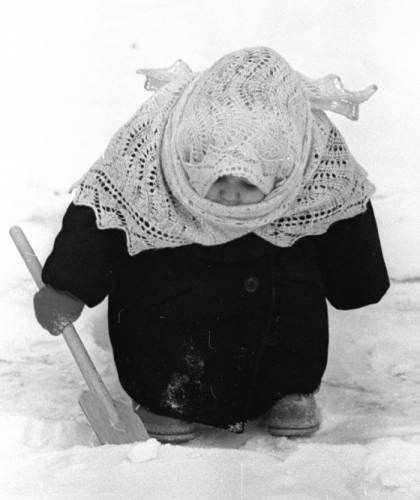 Смешная малышка, закутанная в пуховый платок зимой