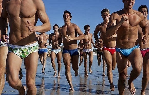 красивые спортивные парни бегут по берегу моря