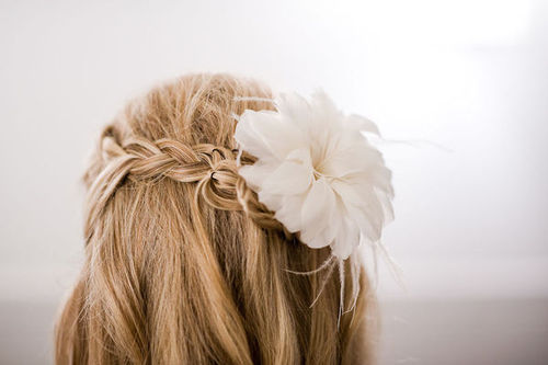 Белый цветок в волосах блондинки с косичкой