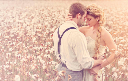 Объятия парня и девушки с косой в цветочном поле