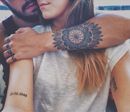 Парень с татуировками на руках обнимает девушку