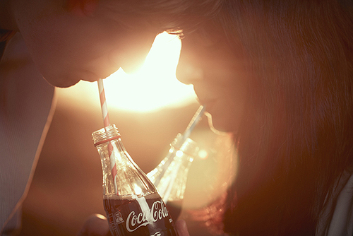 Парень и девушка пьют колу на фоне солнца