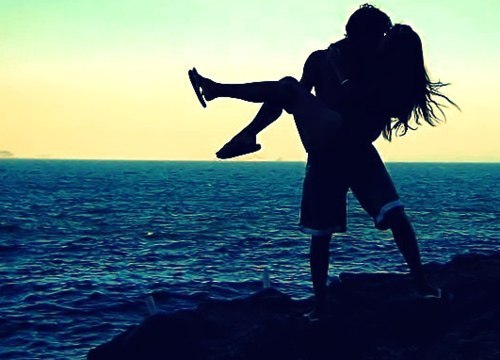 парень держит девушку на руках на фоне моря