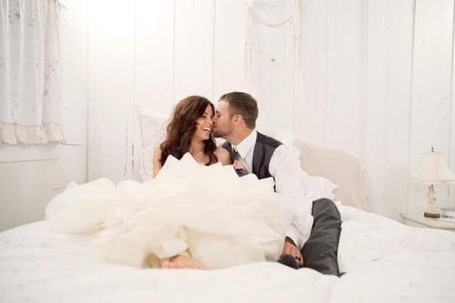 Счастливые жених и невеста смеются на кровати
