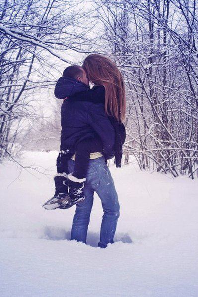 Парень держит девушку на руках в зимнем лесу