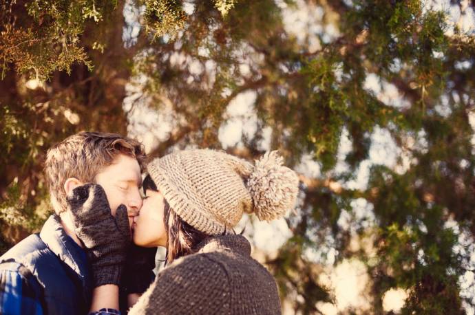 Девушка в вязаной шапочке целует парня в губы