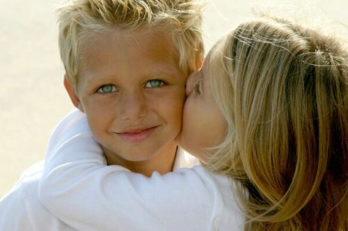 Девочка целует мальчика с голубыми глазами