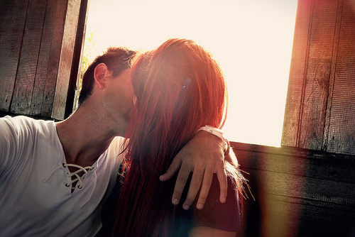 Парень целует девушку с рыжими волосами