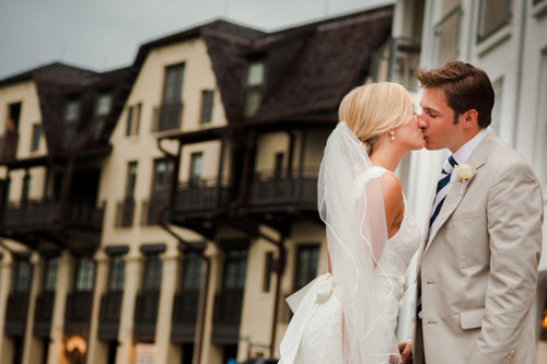 Жених и невеста целуются на фоне зданий