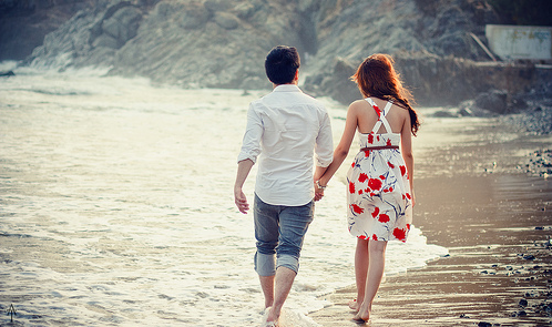 Парень и девушка идут по берегу, держась за руки