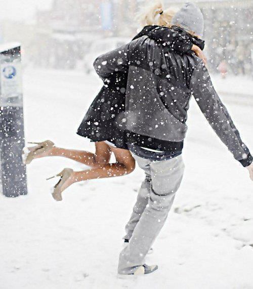 Парень приподнял девушку в туфлях в снегопад