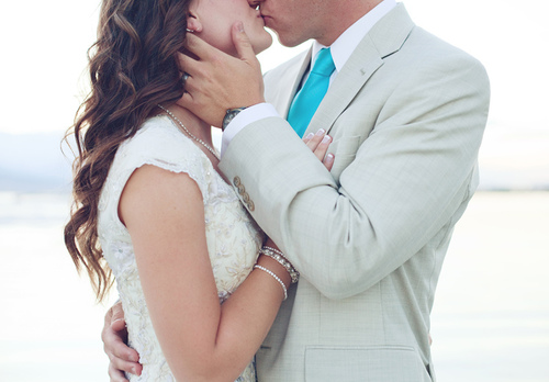Жених в белом костюме целует невесту