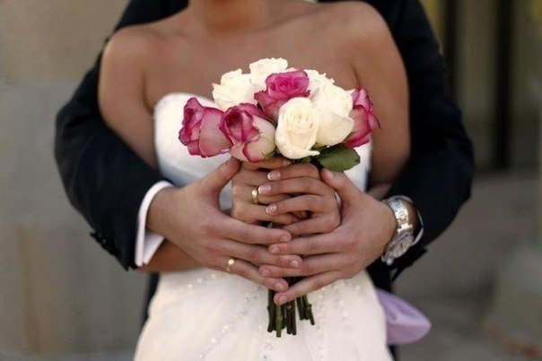 невеста с букетом и руки жениха,обнимающие невесту