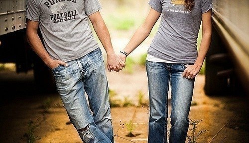 парень и девушка в джинсах держатся за руки