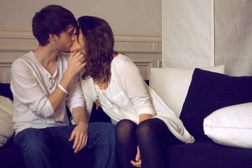 парень целует девушку сидя на диване