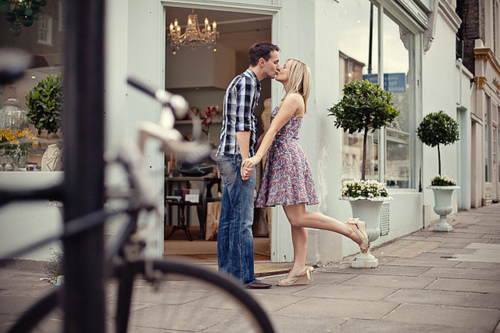 Девушка в цветастом сарафане целует парня у магази