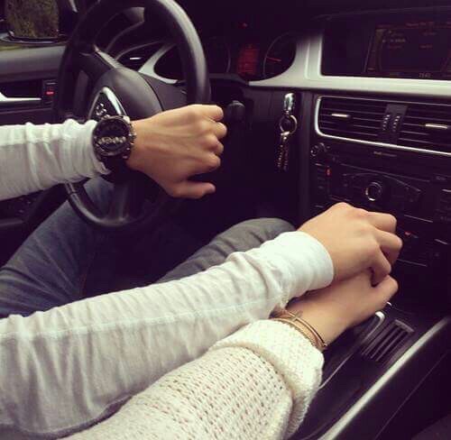 Парень держит девушку за руку в машине