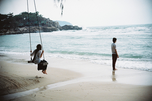 Парень и девушка на качелях на берегу моря