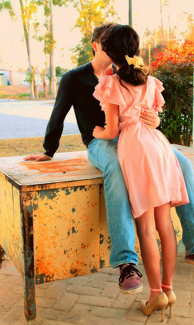 Девушка в розовом платье целует парня в джинсах