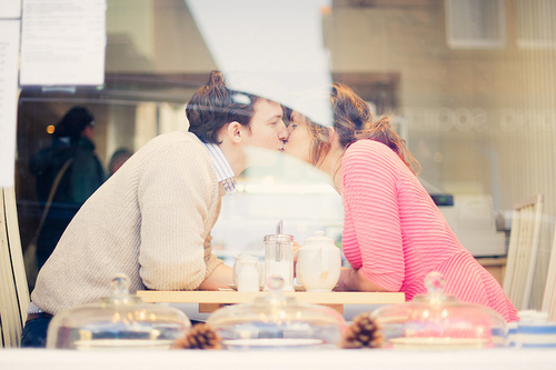 Парень с девушкой целуются сидя за столиком в кафе