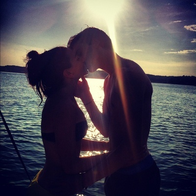 Парень с девушкой целуются у моря в лучах солнца