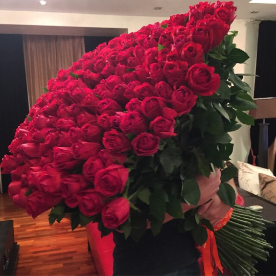 Огромный букет красных роз в руках девушки