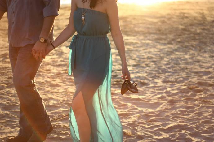 Парень с девушкой держась за руки идут по берегу