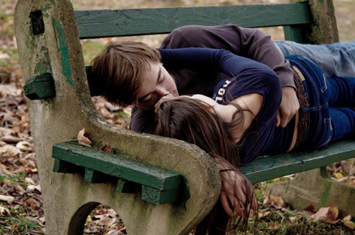Парень с девушкой целуются на скамейке