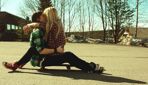 Парень с девушкой вдвоем на скейте целуются